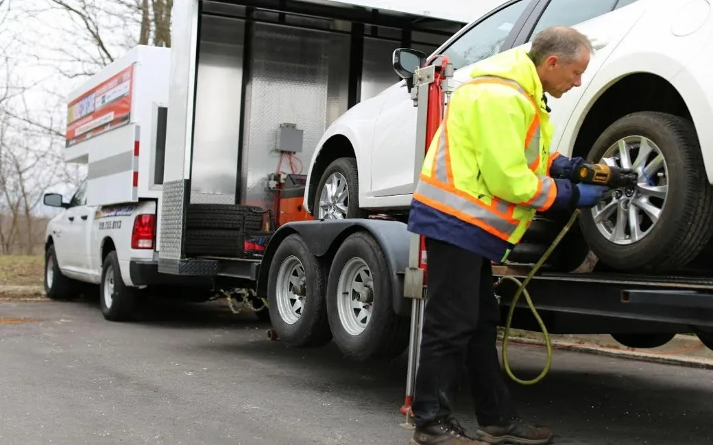 The mobile lift trailer, loaded with a vehicle for on-site wheel service